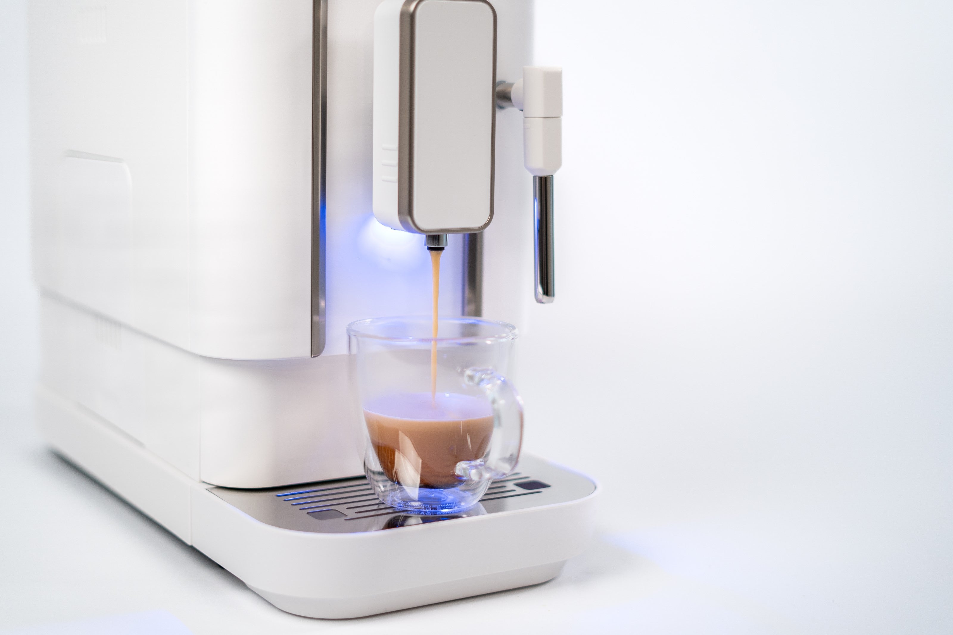 Close-up of diamond white espresso machine dispensing from spout into a glass cup