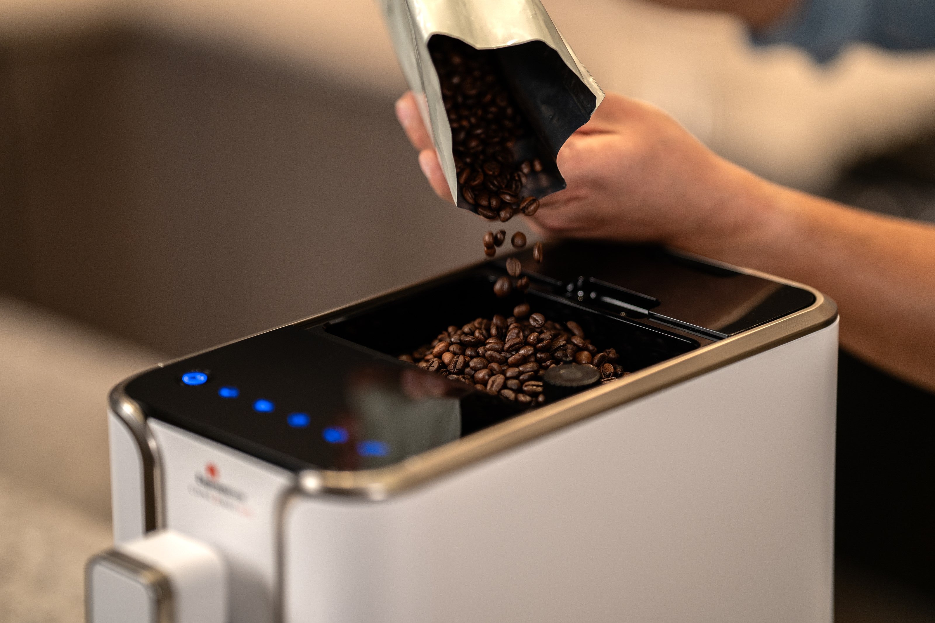 Diamond white espresso machine with bean hopper open, coffee beans being added