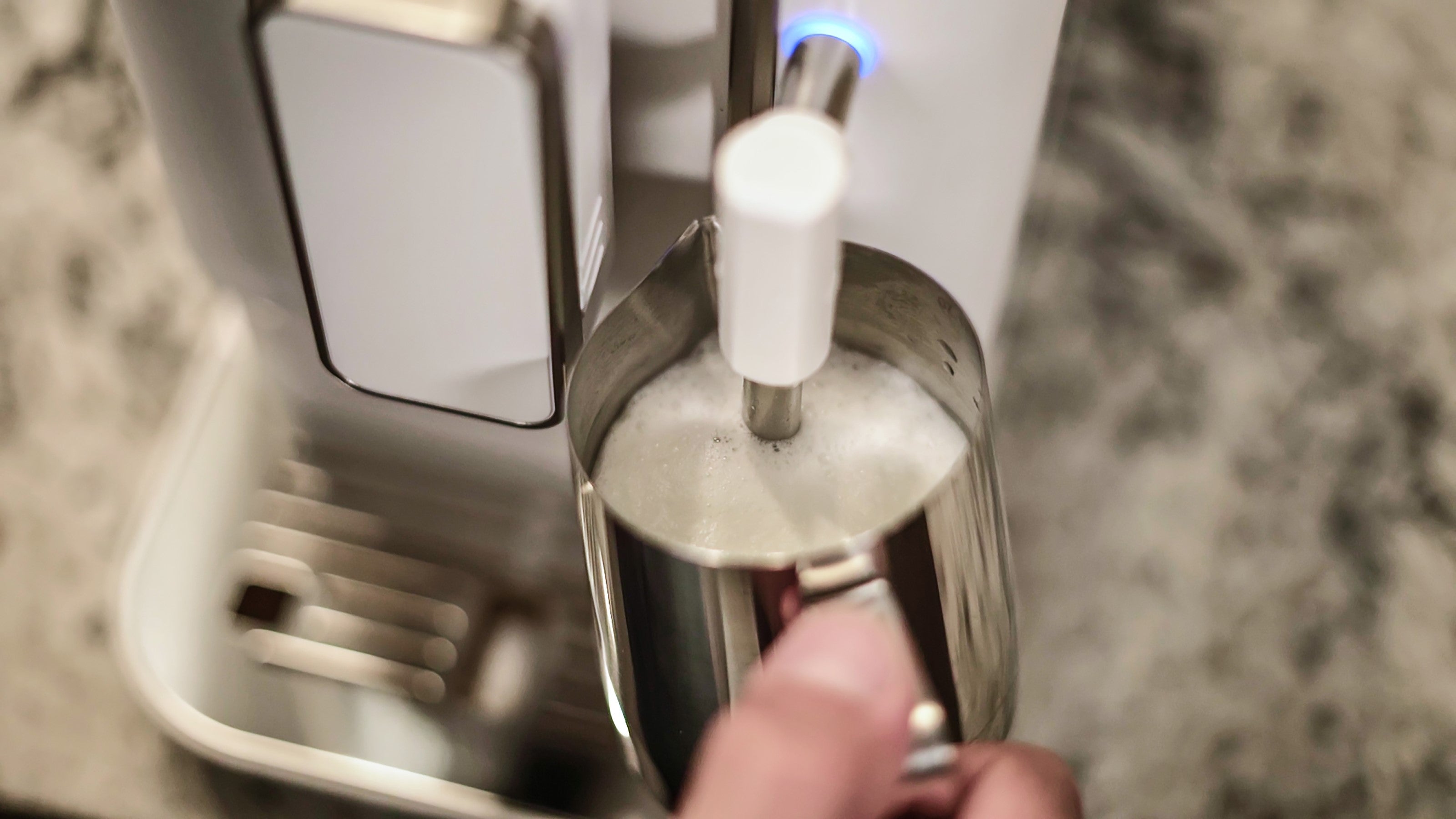 Diamond white espresso machine brewing spout dispensing into a clear carafe