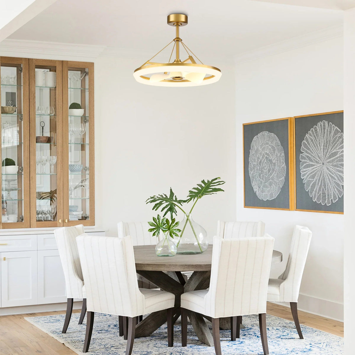 Gold ceiling fan over a dining set in a bright living room with white walls.