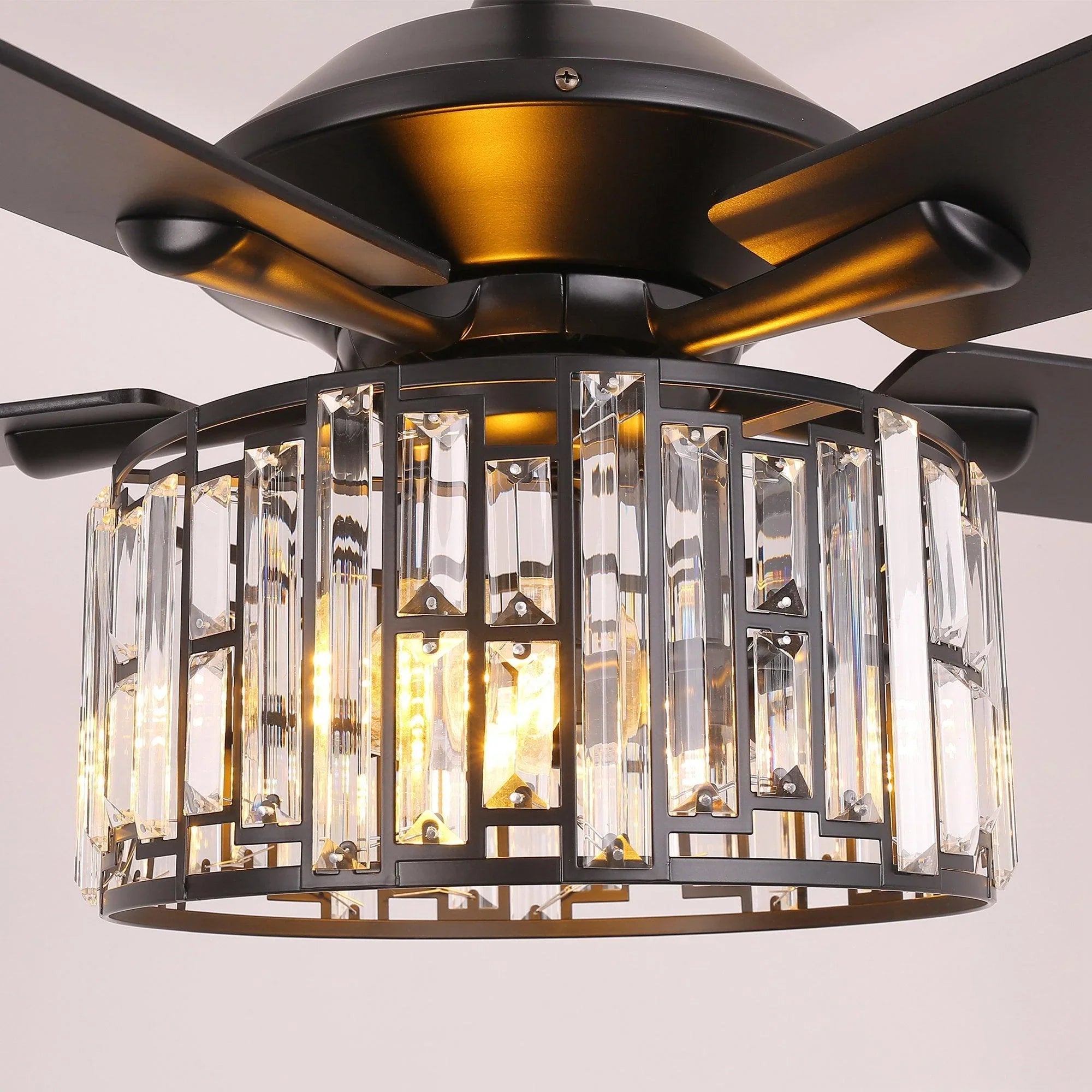 Ceiling fan crystal light drum close-up with warm bulbs inside a dark metal frame.