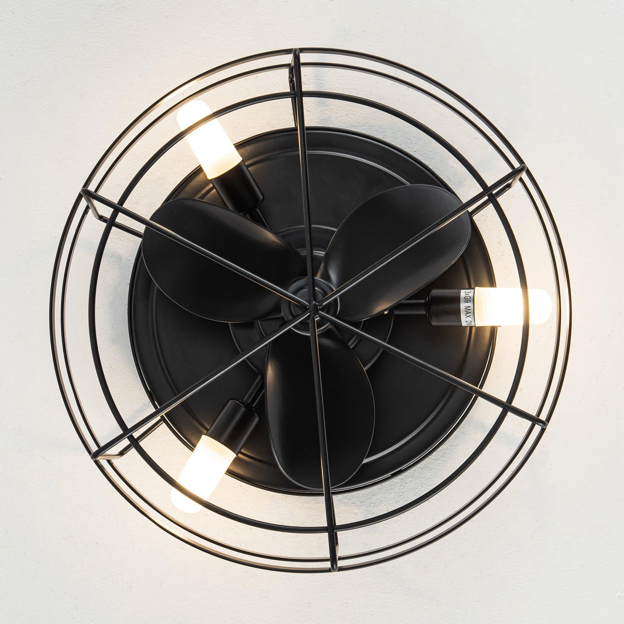Black ceiling fan with 4-blade design behind wire cage and warm light