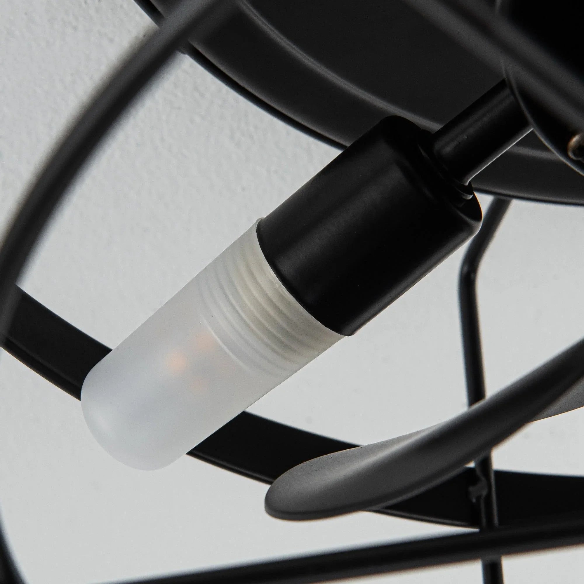 Close-up of black ceiling fan light socket and bulb inside metal cage