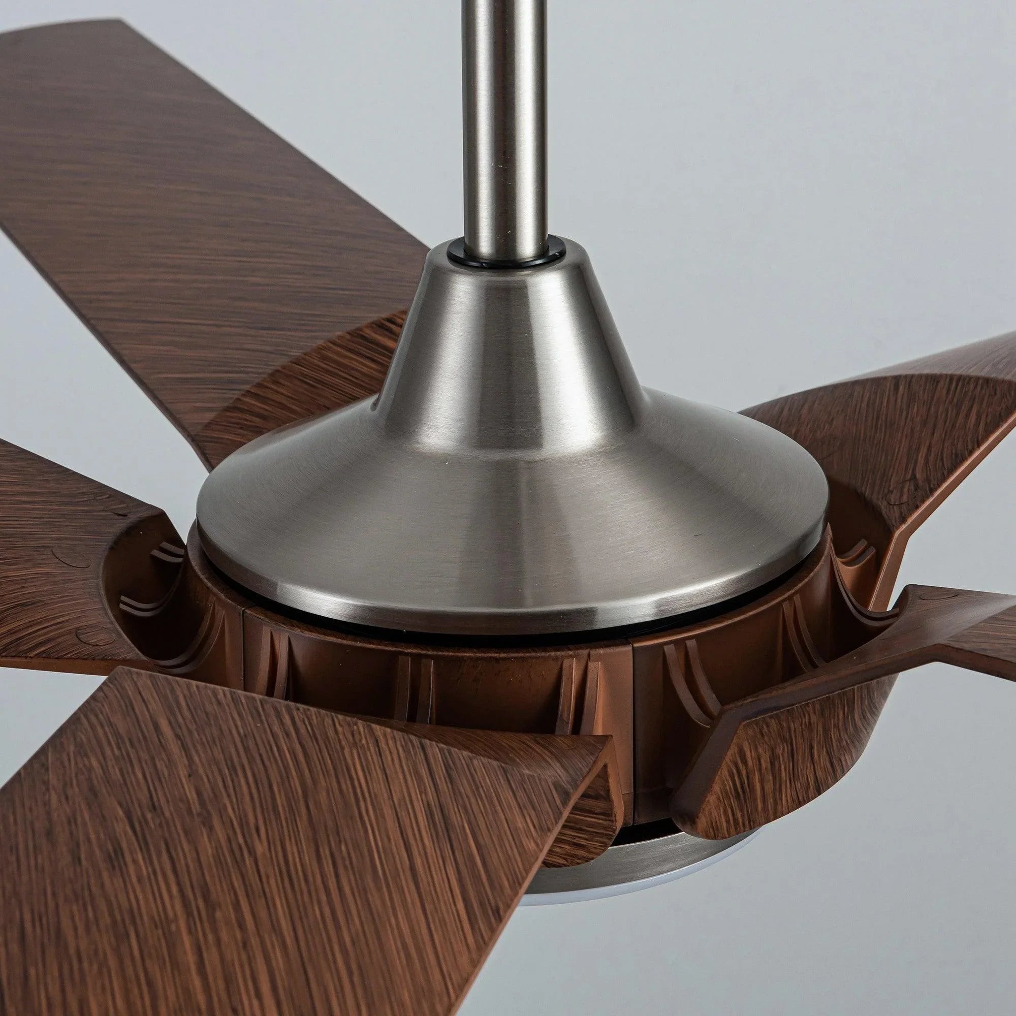 Ceiling fan motor housing with warm wood blades and brushed nickel downrod mount