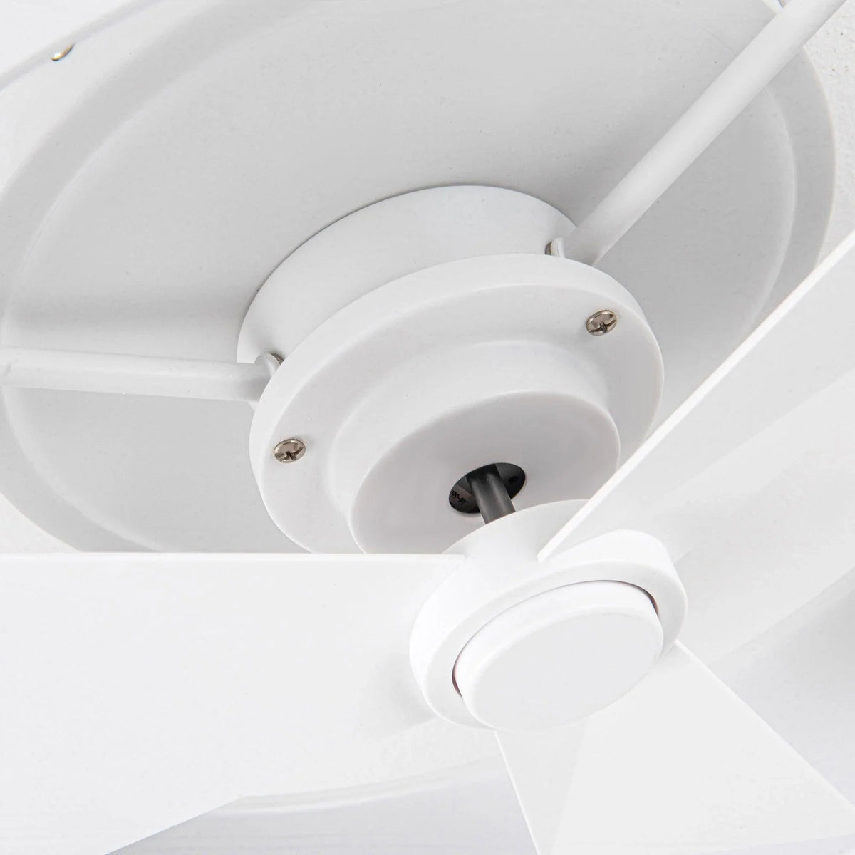 White ceiling fan motor hub with three blades and mounting bracket close-up