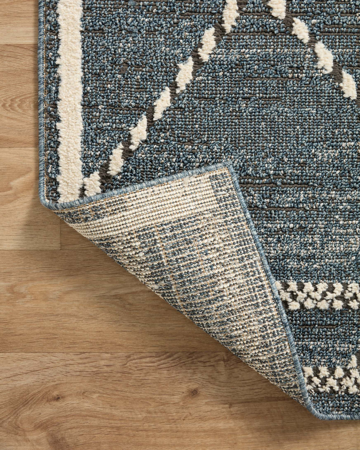 Blue-gray area rug with ivory border; corner rolled edge shows textured weave