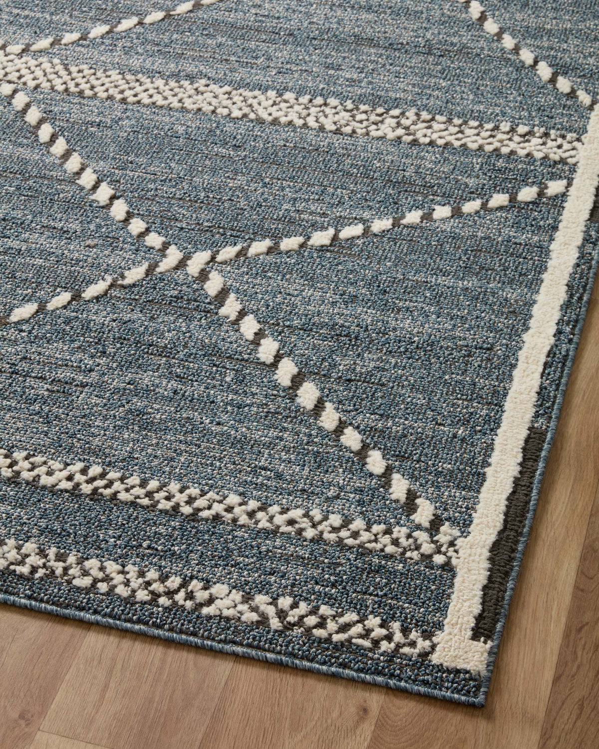 Denim-blue area rug with cream accent bands and thick braided trim