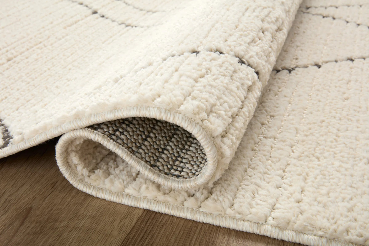 Ivory runner rug with charcoal lattice, folded edge showing low-pile texture