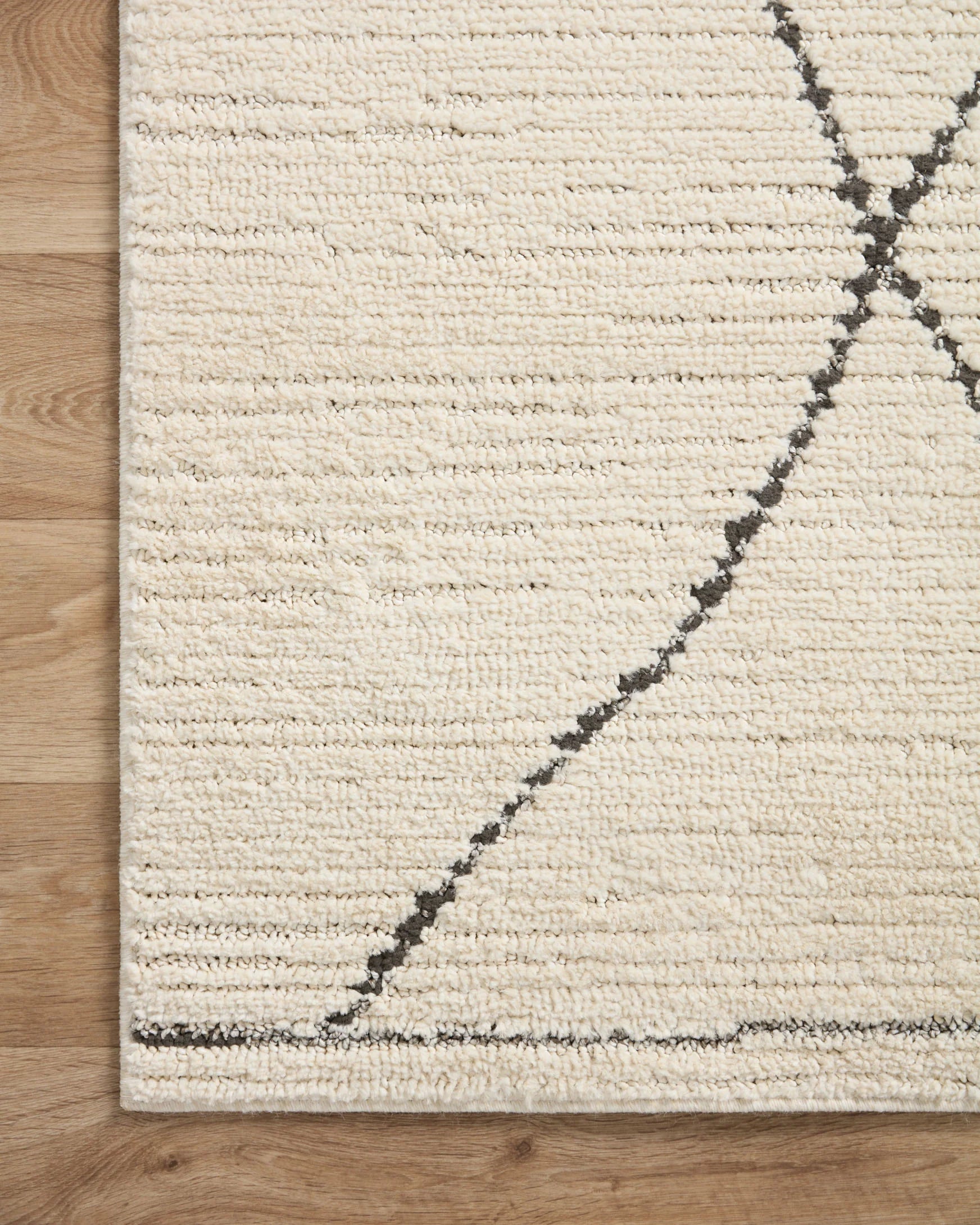 Ivory rug corner with charcoal diagonal diamond line pattern, low pile