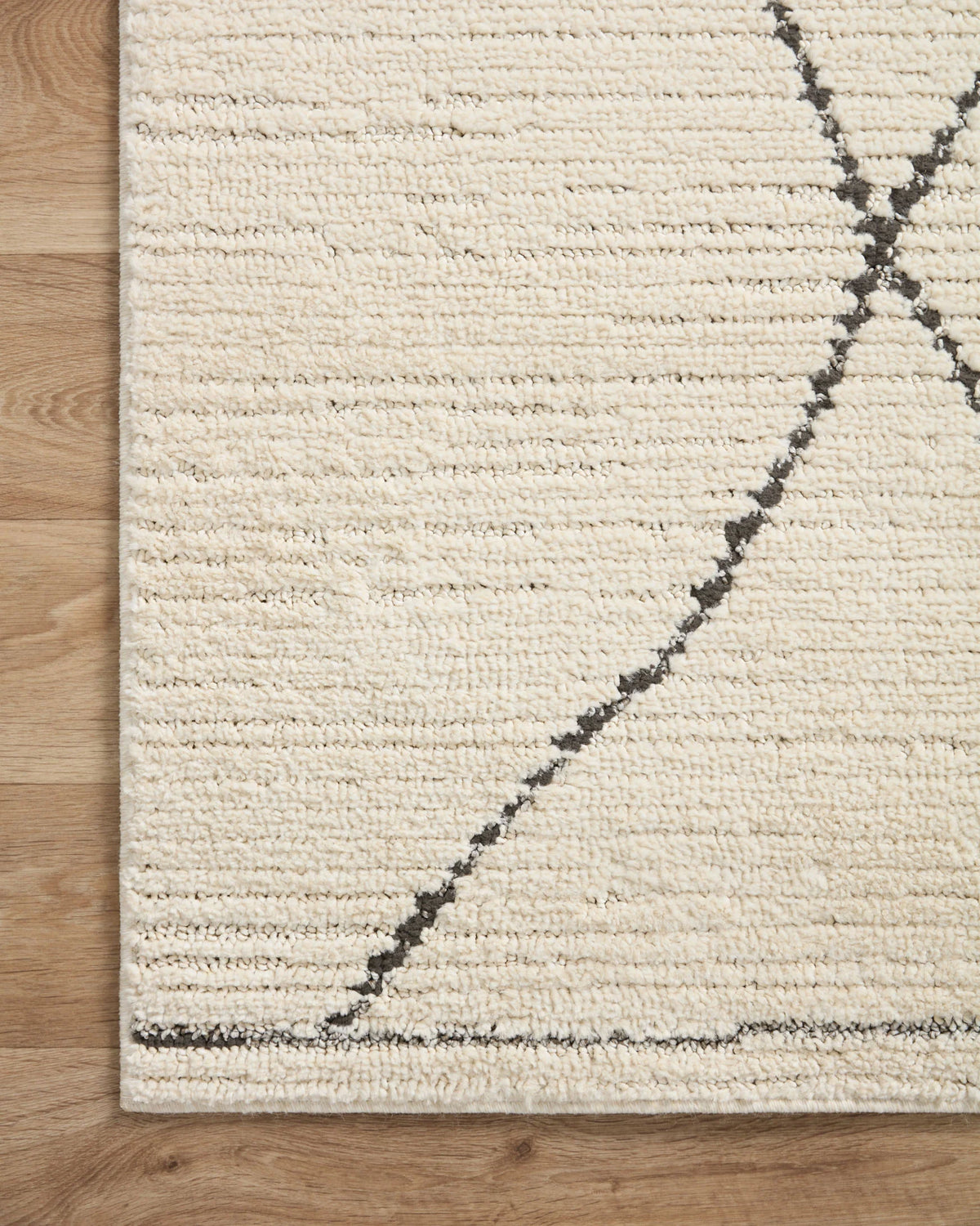 Ivory runner rug corner with charcoal lattice and curved line accent detail