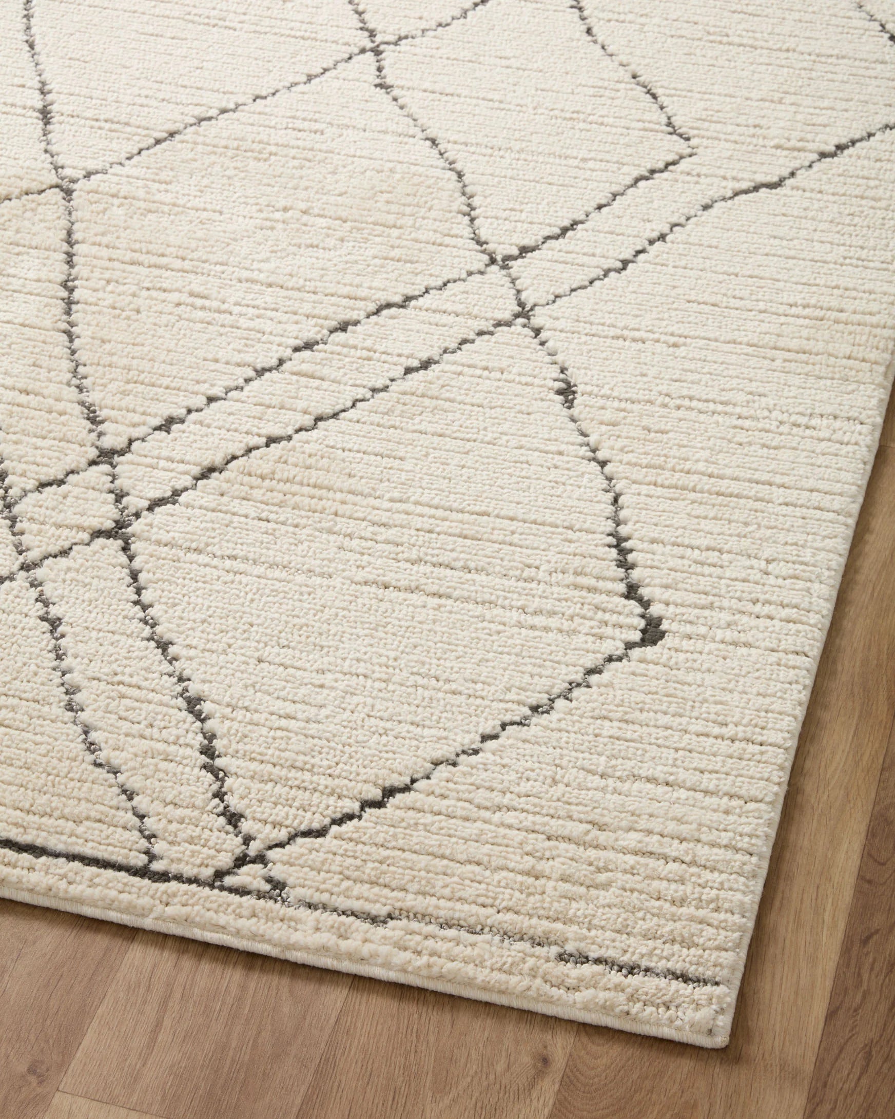 Overhead view of ivory area rug featuring charcoal diamond grid lines.