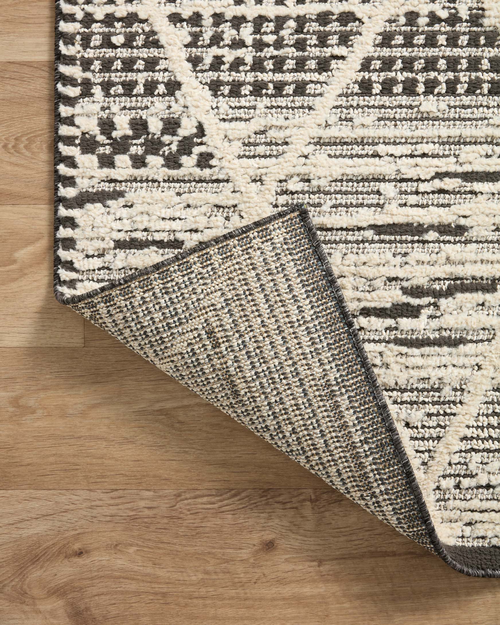 Charcoal and ivory area rug folded corner detail showing dense woven texture