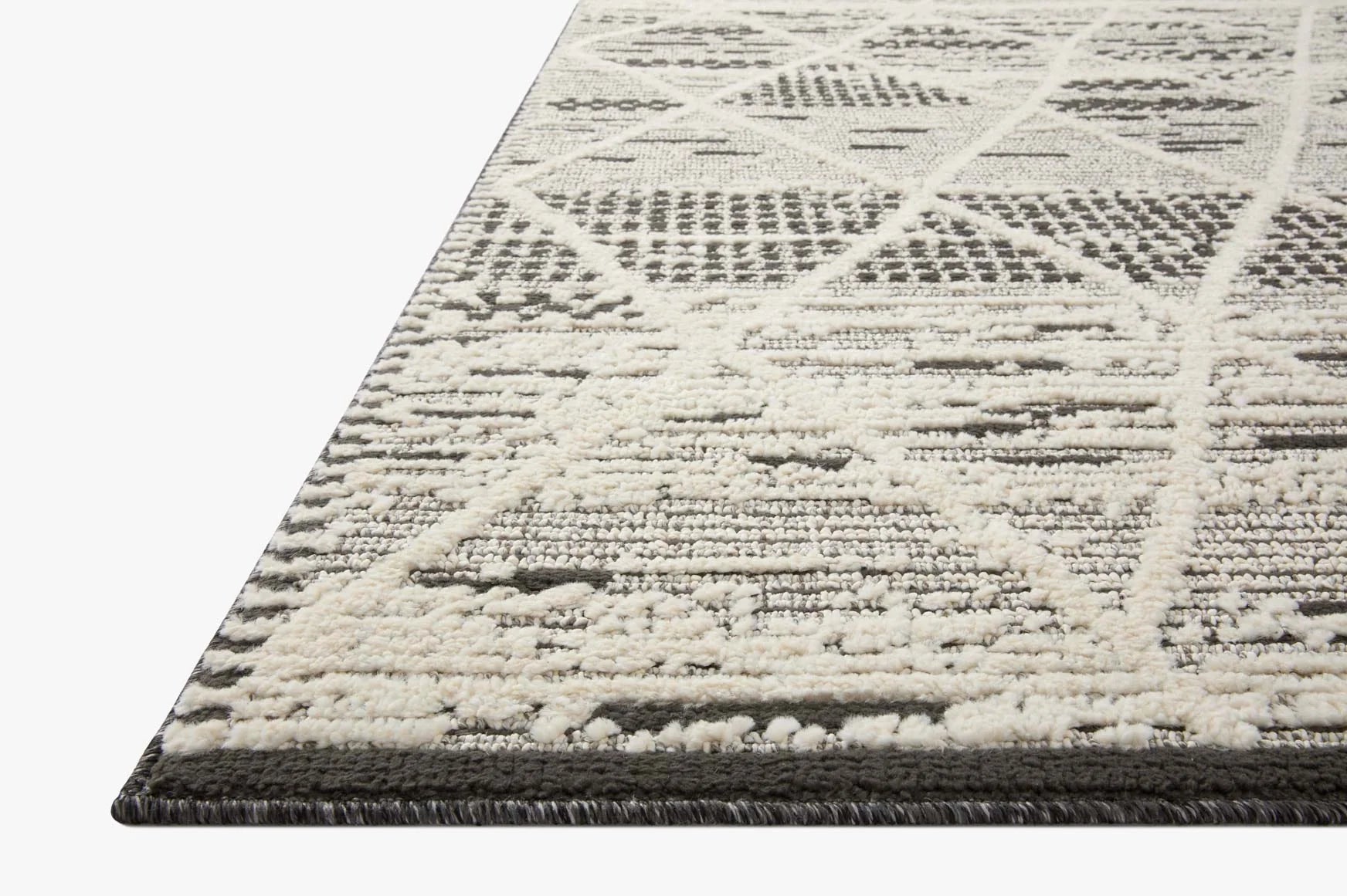 Charcoal and ivory accent rug with patterned tribal blocks and dark fringed border edge