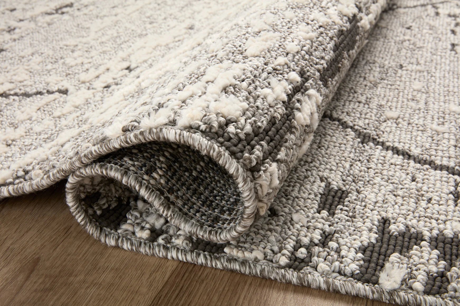 Grey and charcoal area rug with textured short pile and stitched, fringed-look edge