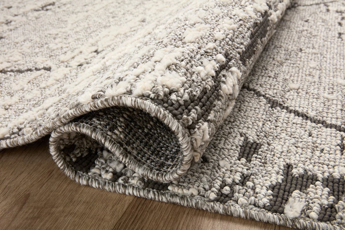Grey textured runner rug corner with rolled edge and fringe