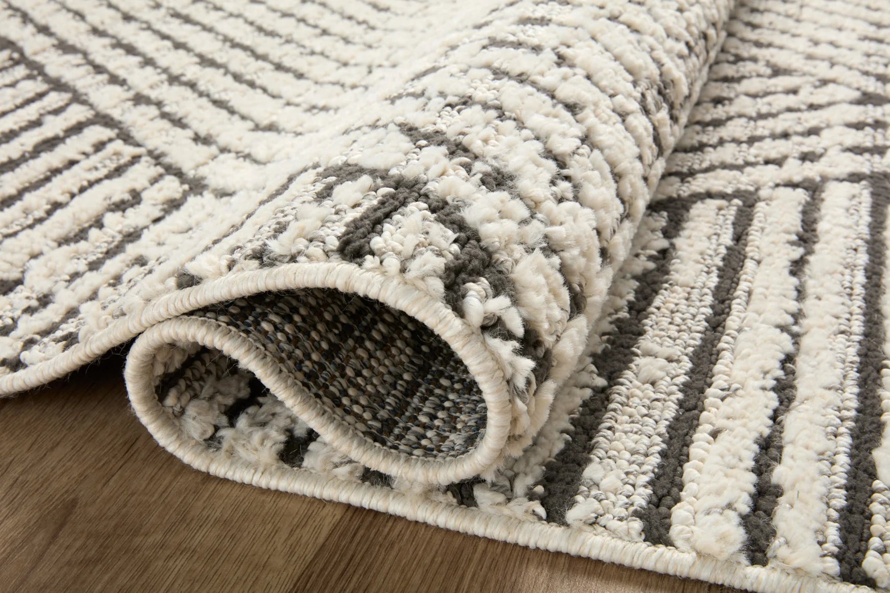 Textured ivory-and-charcoal area rug showing thick pile and folded edge detail.