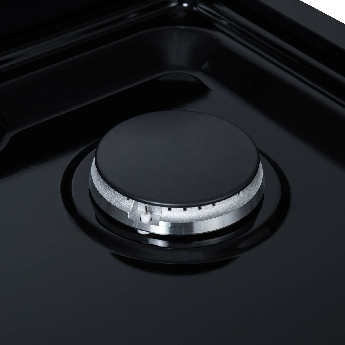 Black gas cooktop burner head with black cap and silver ring, close-up