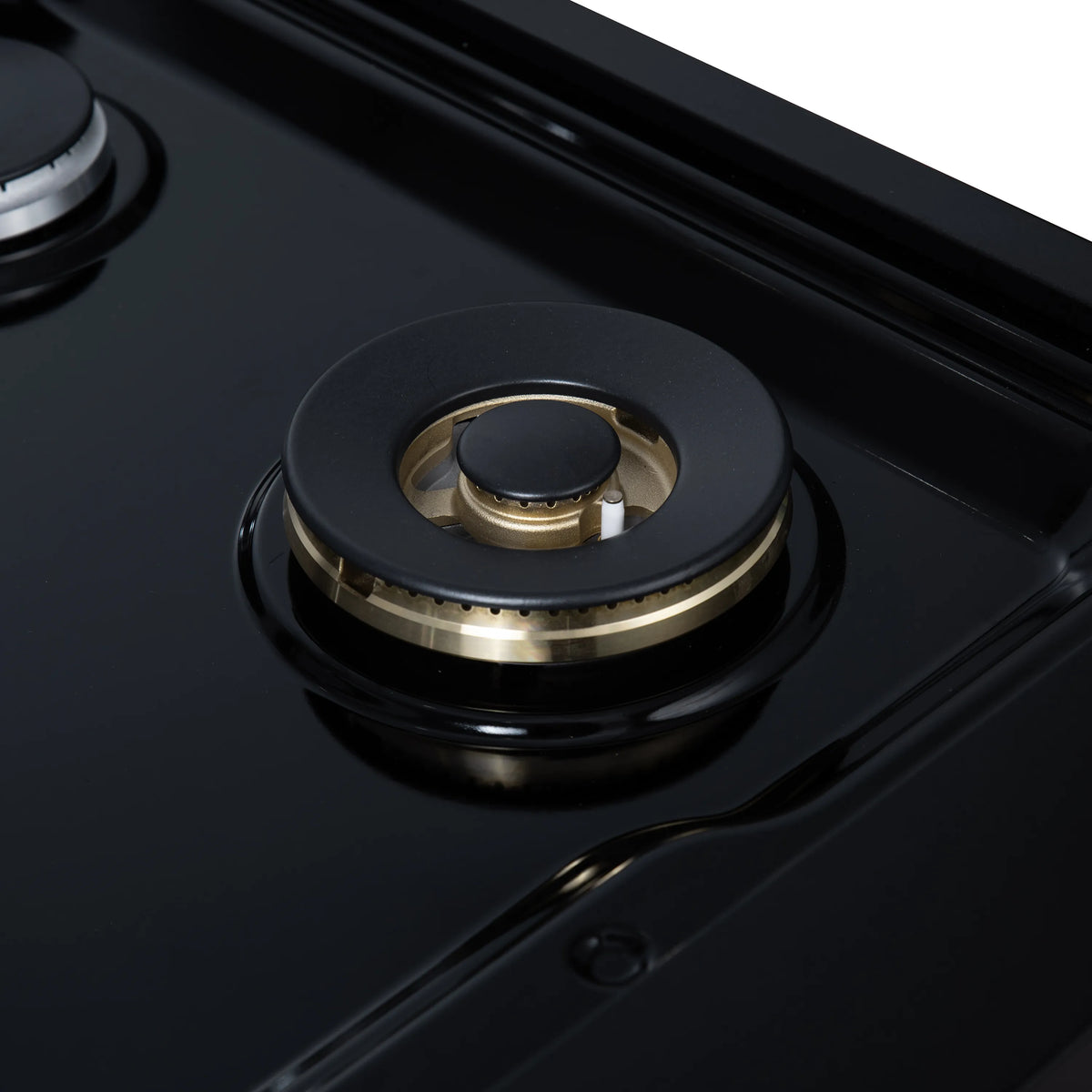 Close-up of black gas burner with brass cap and circular burner ring