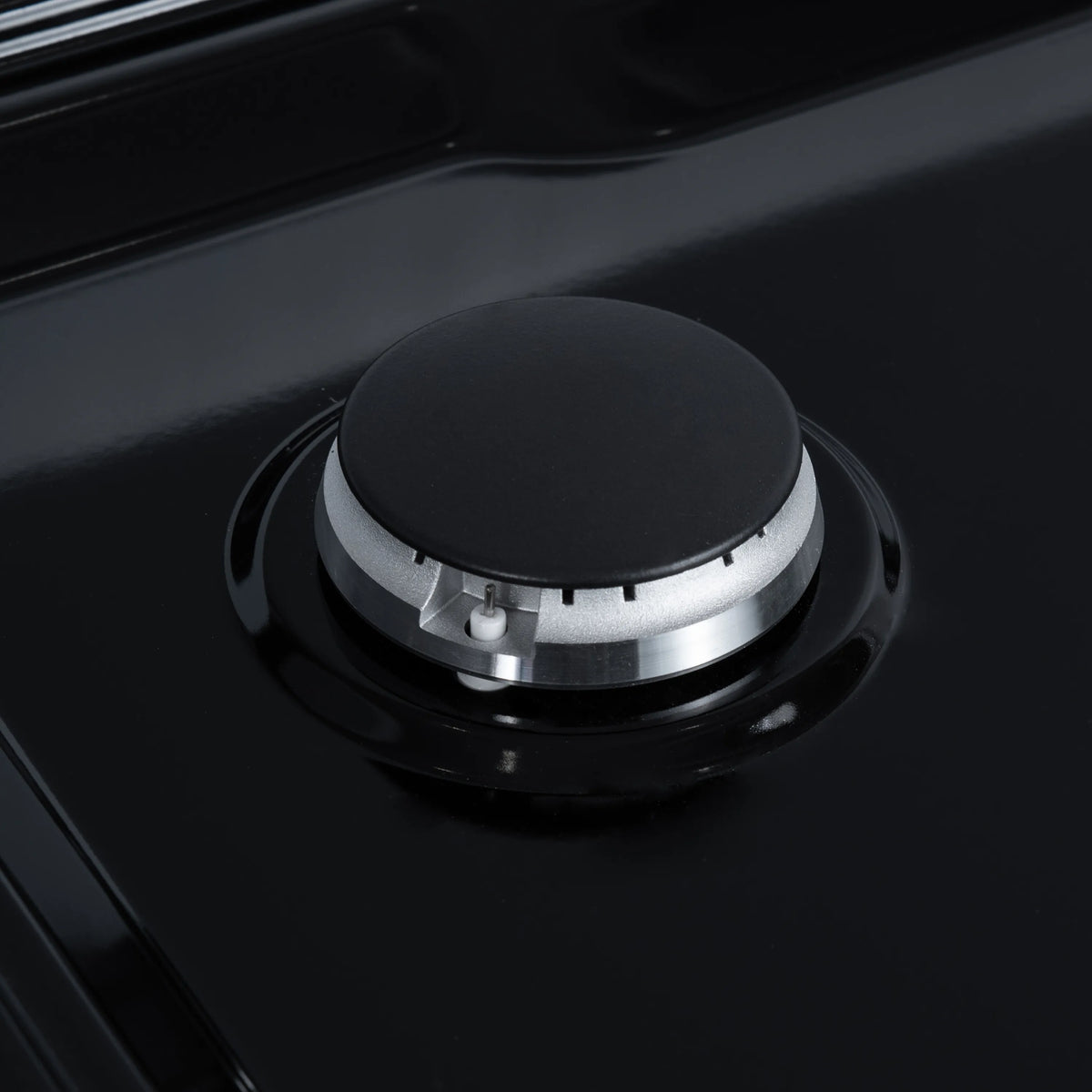 Black burner cap on a gas cooktop with metallic burner base and ring