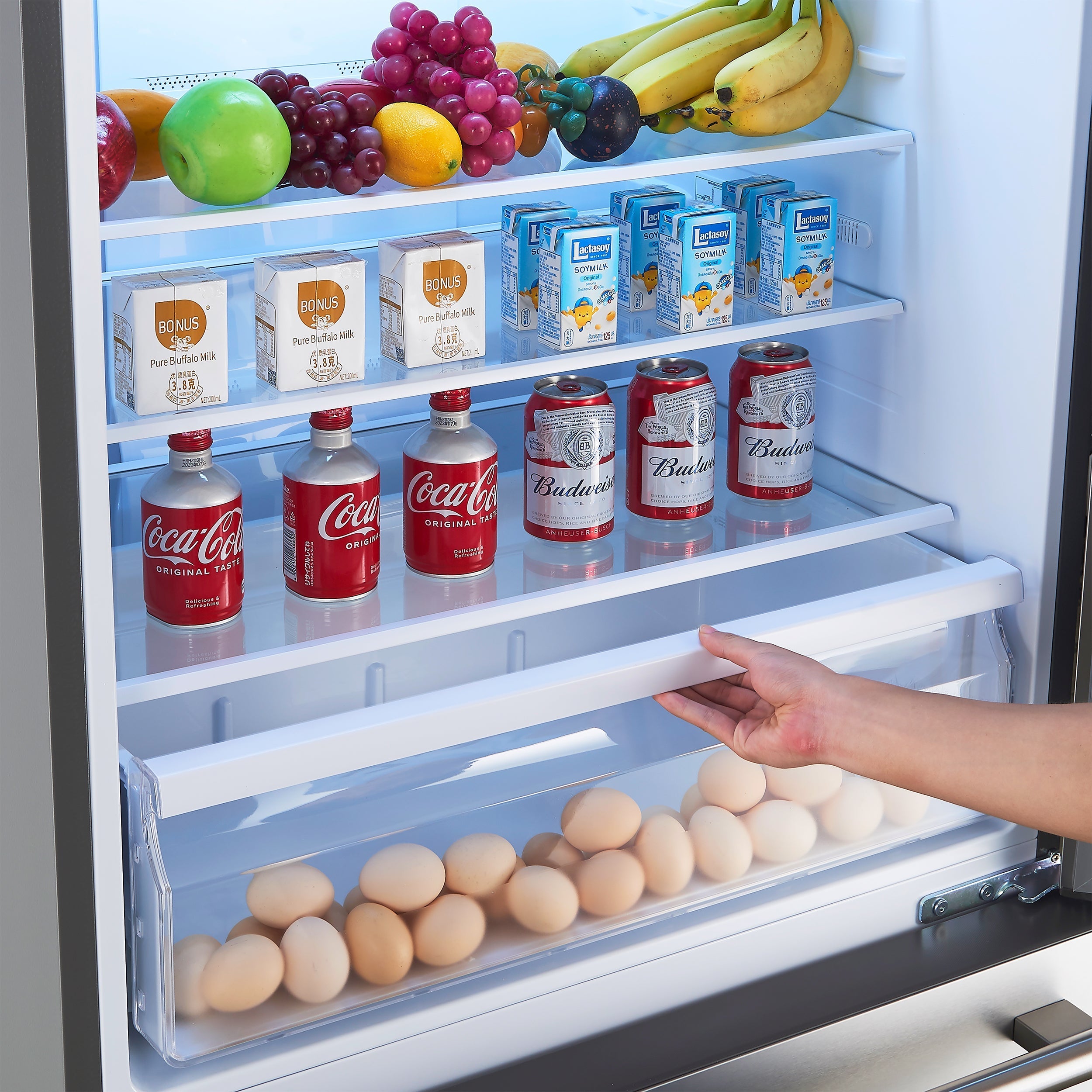 Open refrigerator with fruit, cereal, and drinks on interior shelves