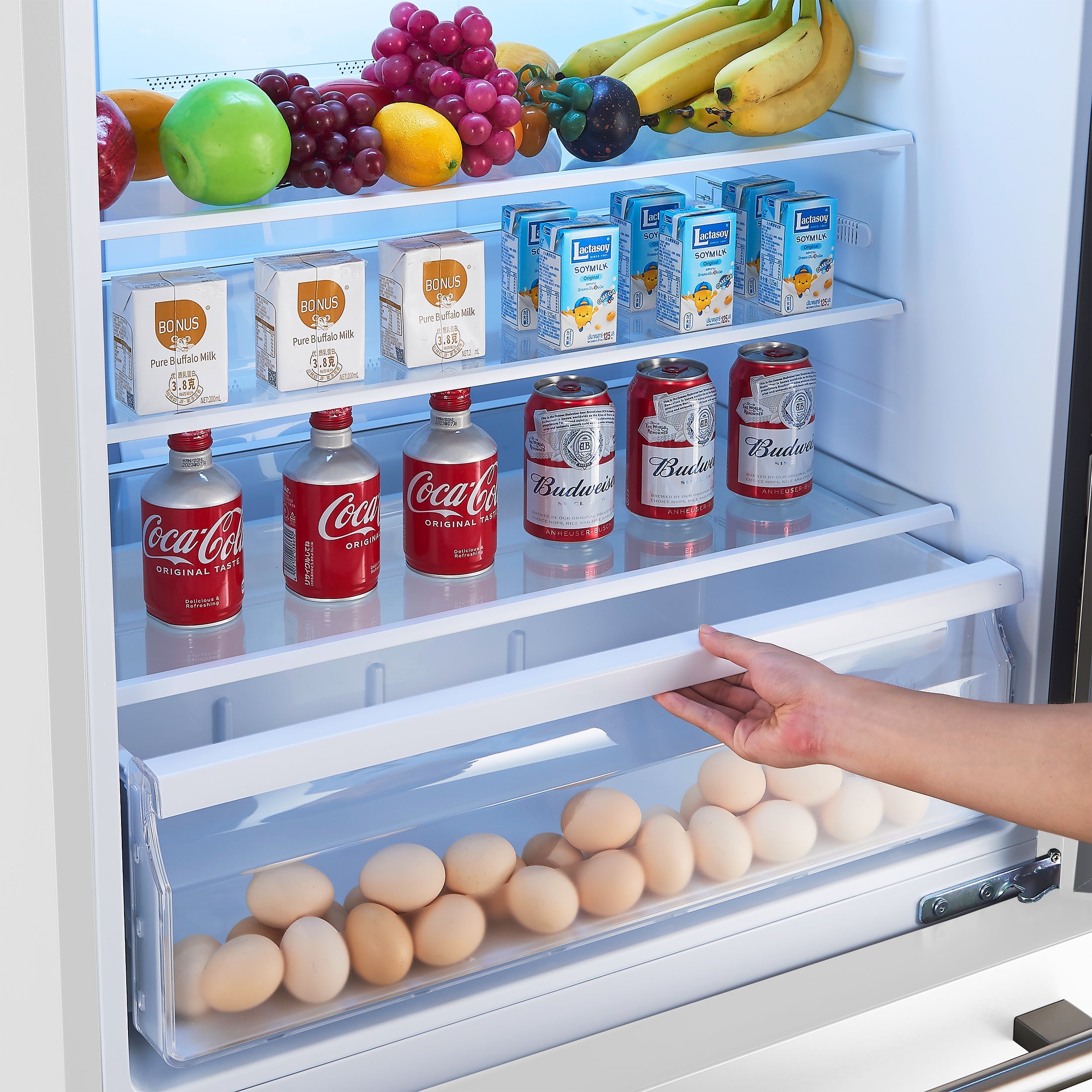 White refrigerator door open with shelves of eggs, drinks, and packaged items