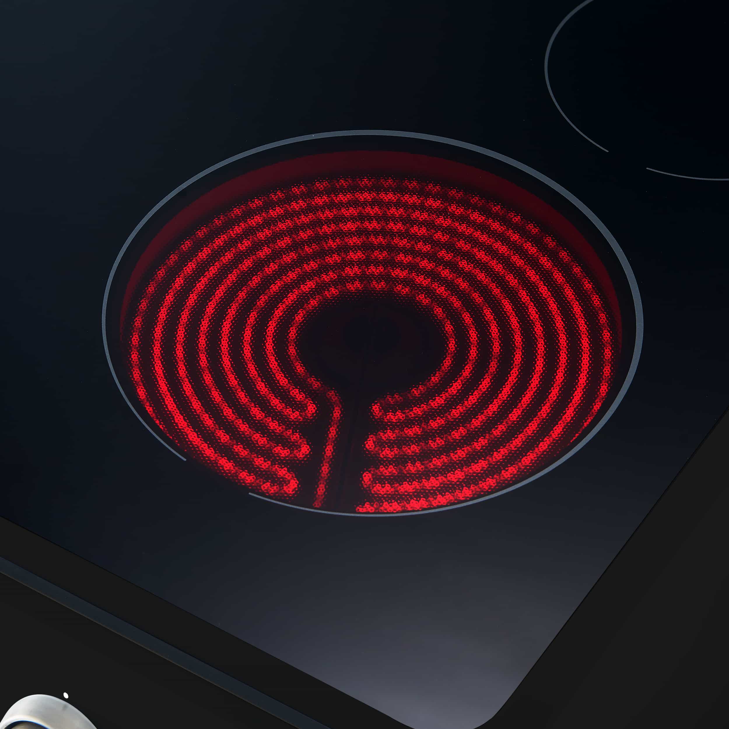 Black electric range cooktop with glowing red coil burner