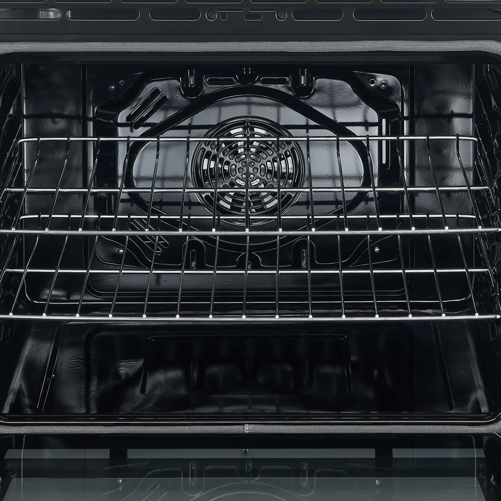 Open oven cavity with black interior and wire racks for electric baking