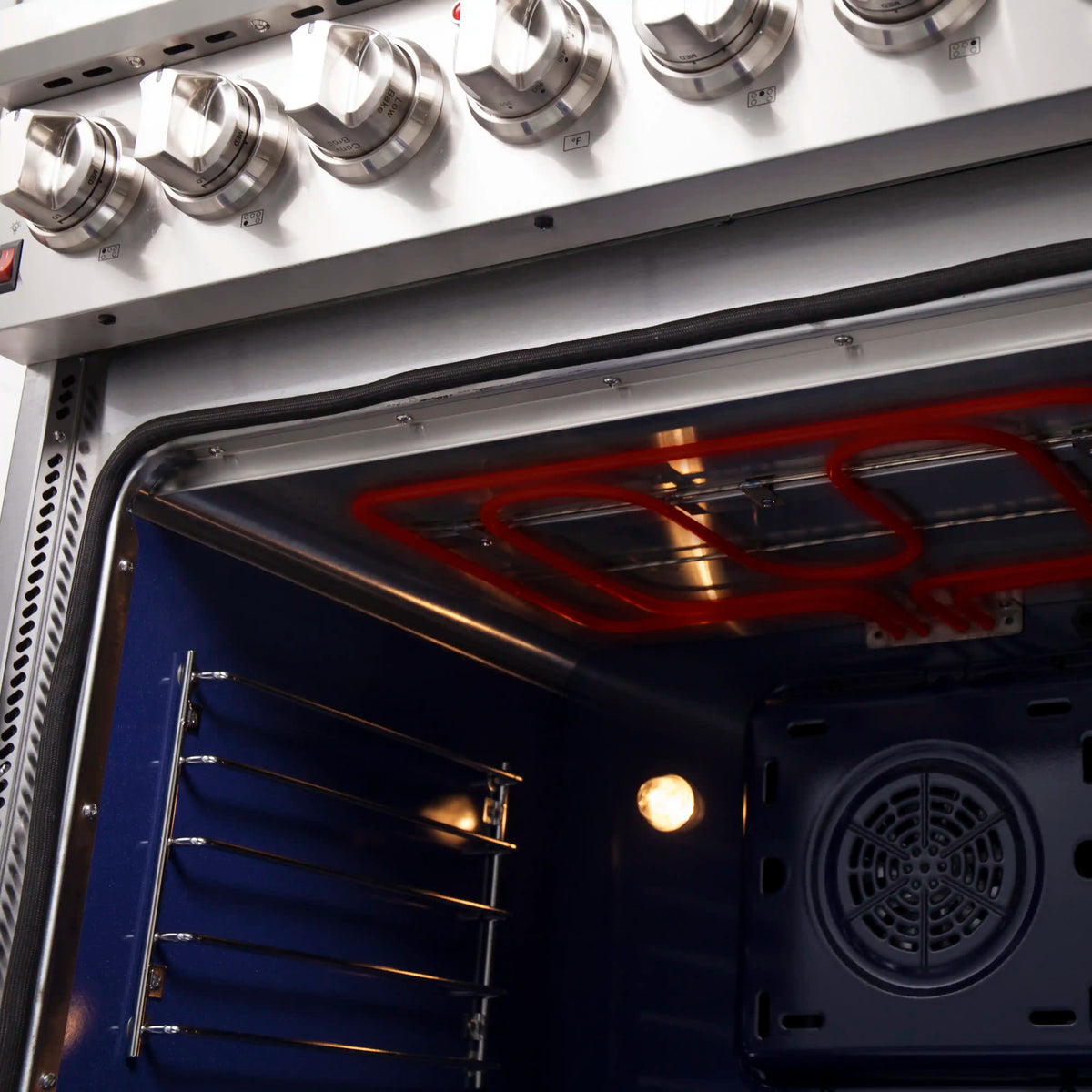 Electric oven with illuminated heating element and fan behind vented panel