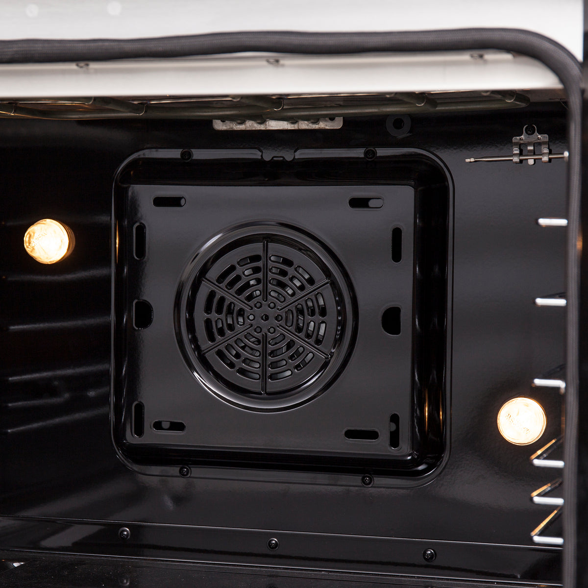 Close-up of electric oven cavity floor with round fan vent opening