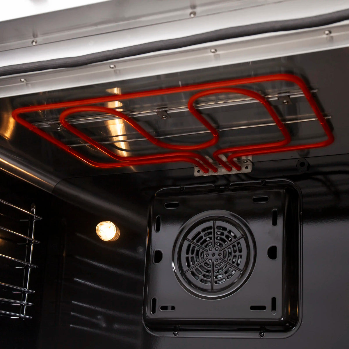 Convection oven fan housing on interior wall with red heating elements