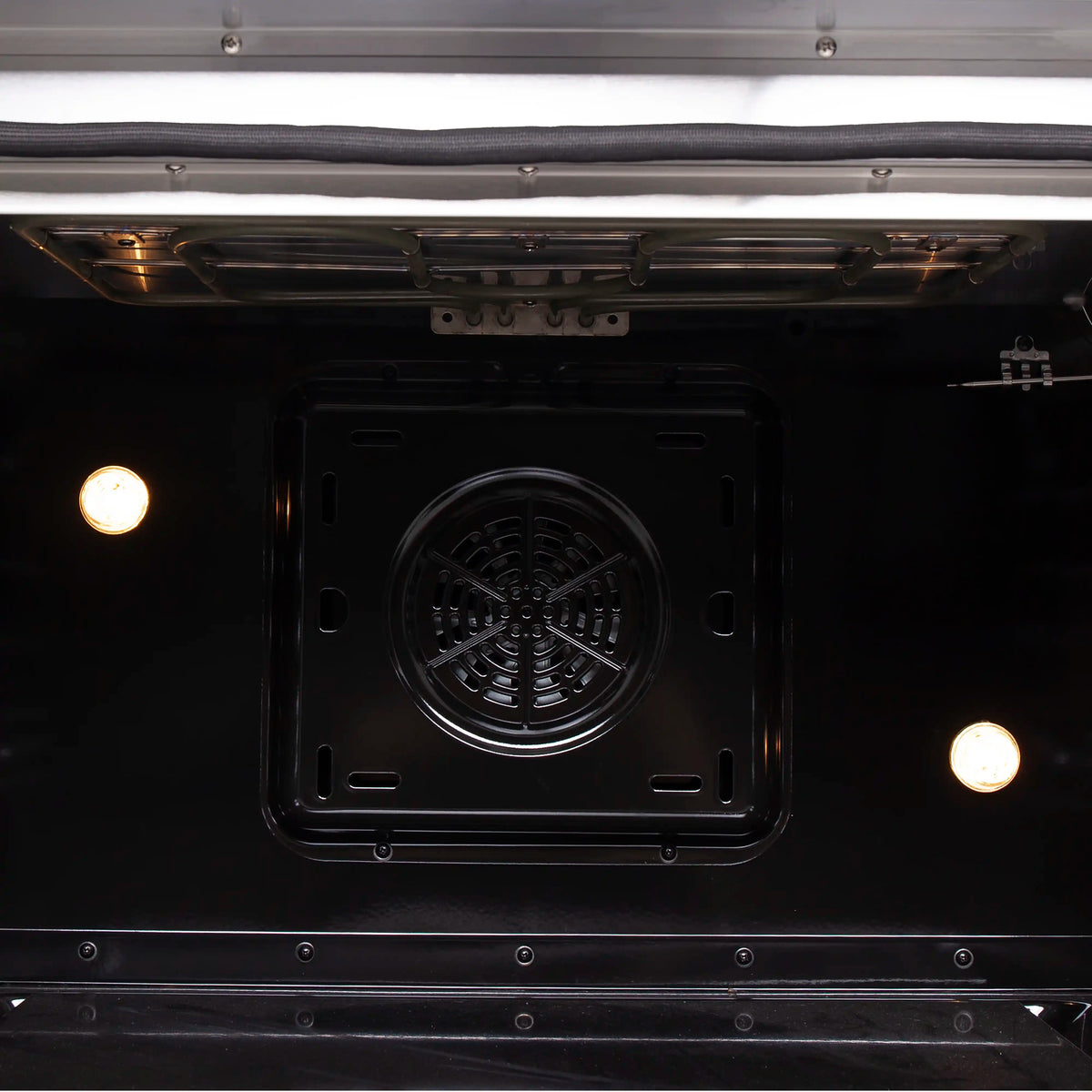 Convection oven interior view with fan housing and oven lights on