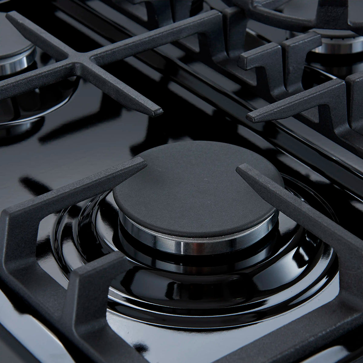 Black gas cooktop with cast-iron grates and round burner caps.