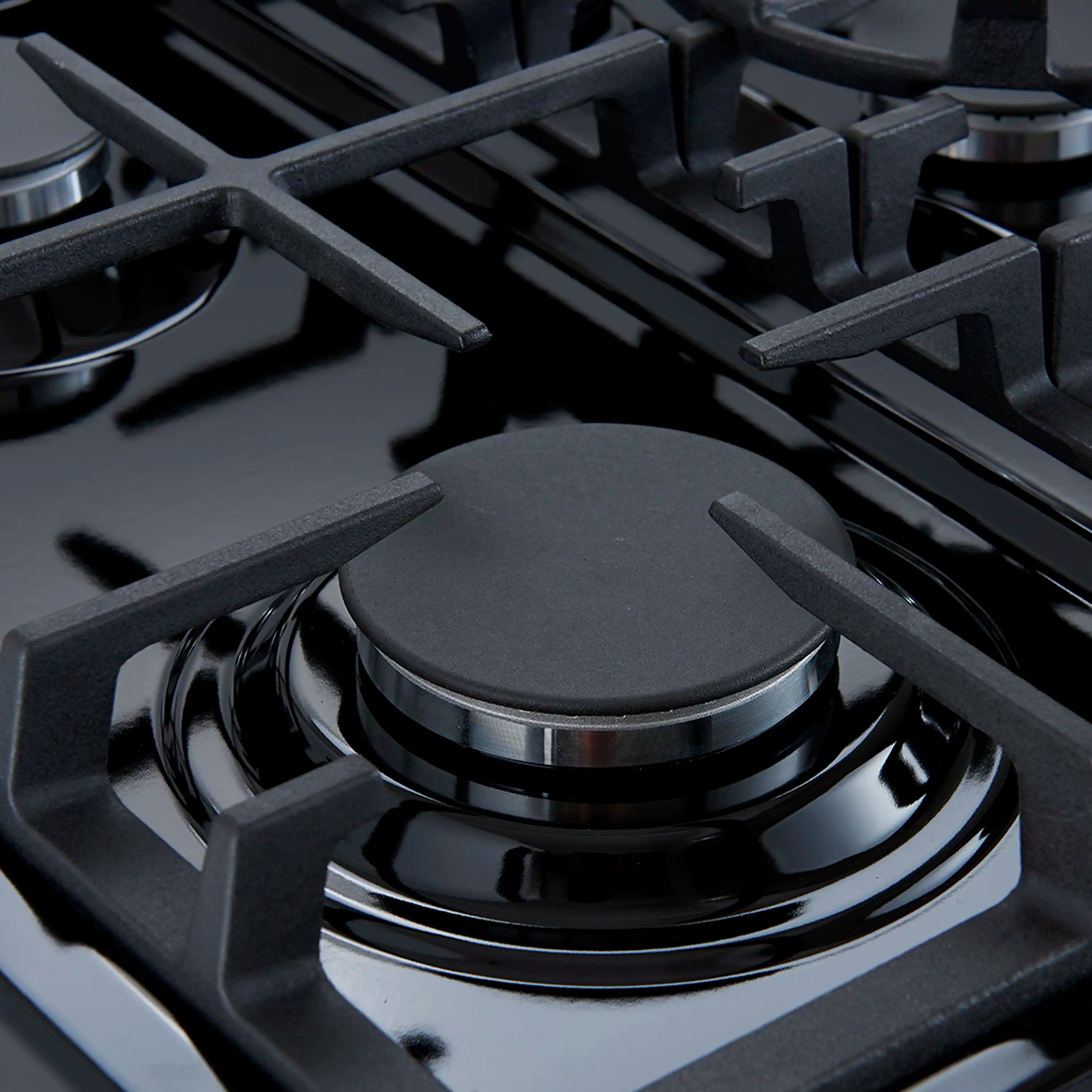 Close-up of black gas cooktop grates and burner on a dark surface