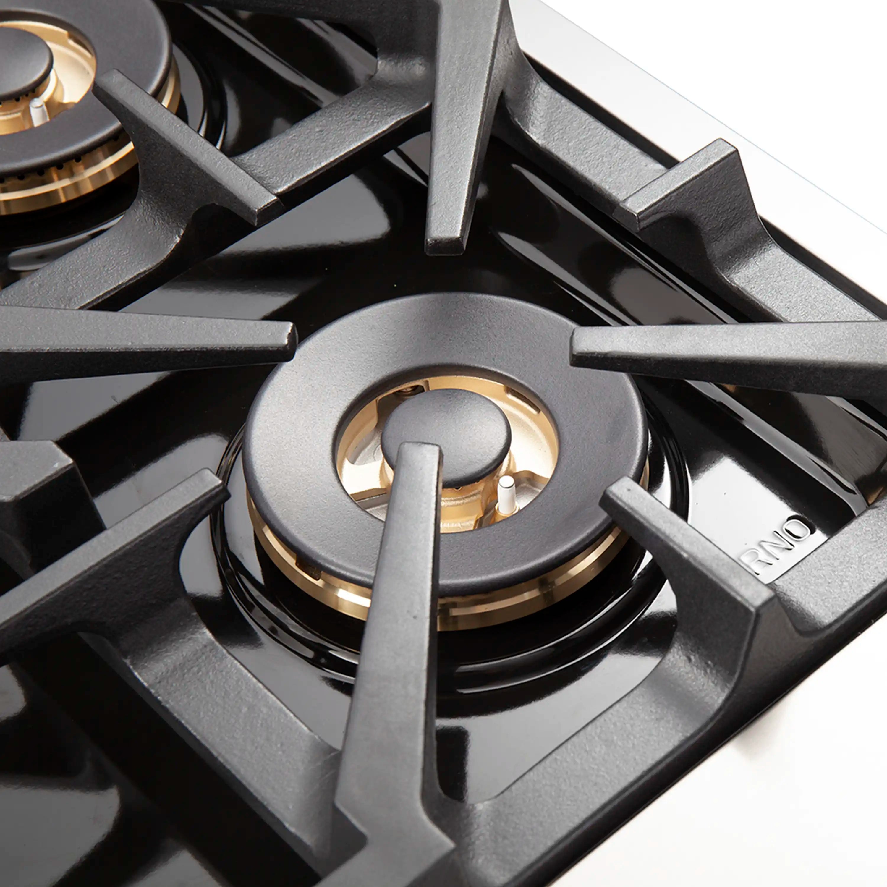 Close-up of gas range burner with black grate and brass-colored cap