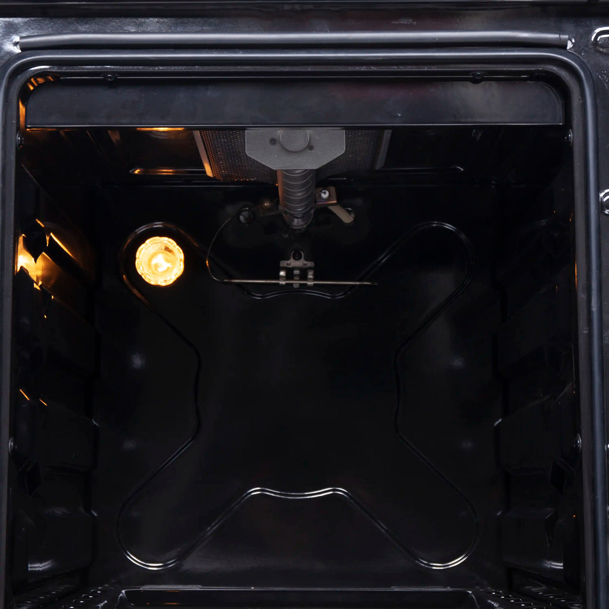 Gas oven cavity showing bottom burner and ignition assembly inside