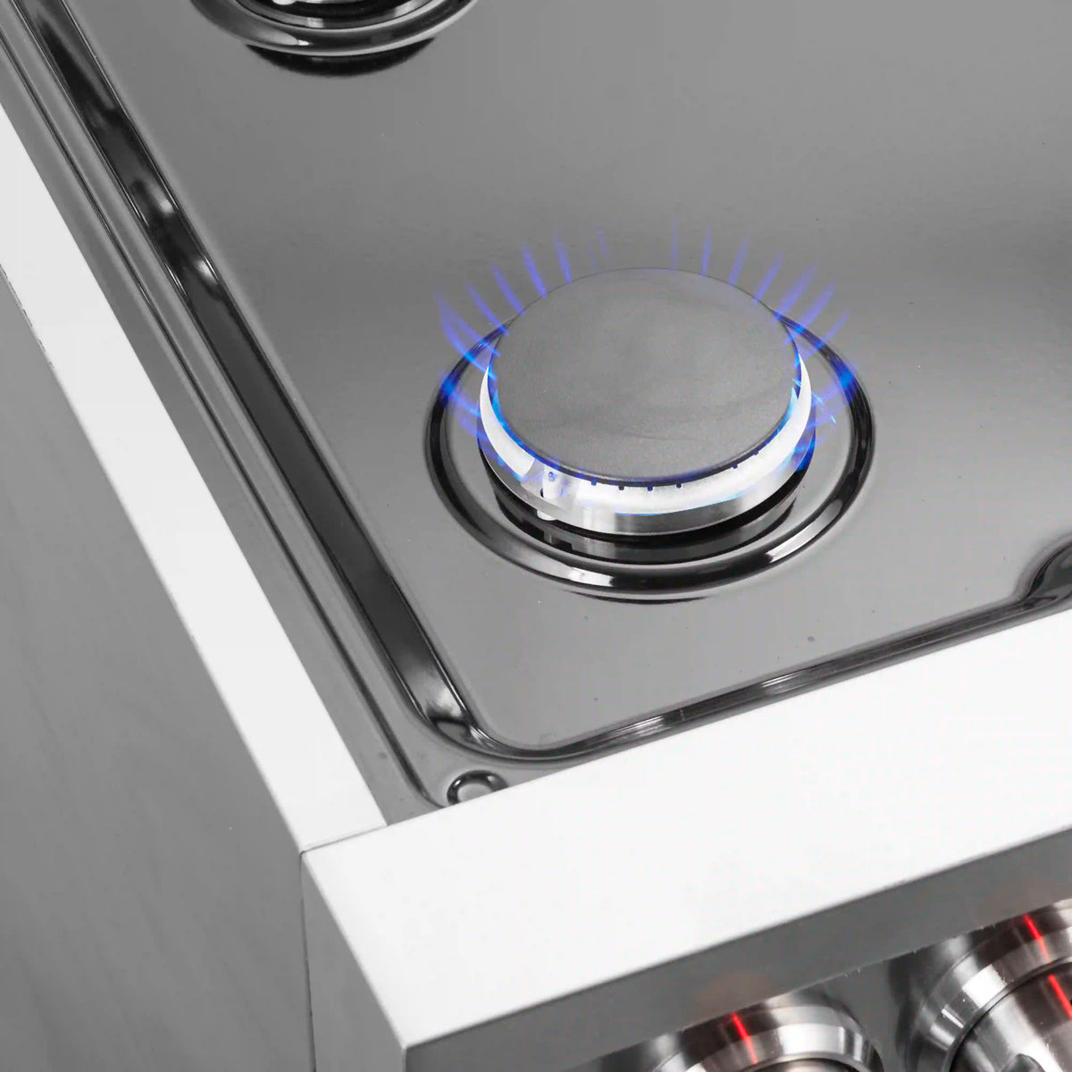 Single gas cooktop burner with blue flame ring on stainless range surface.