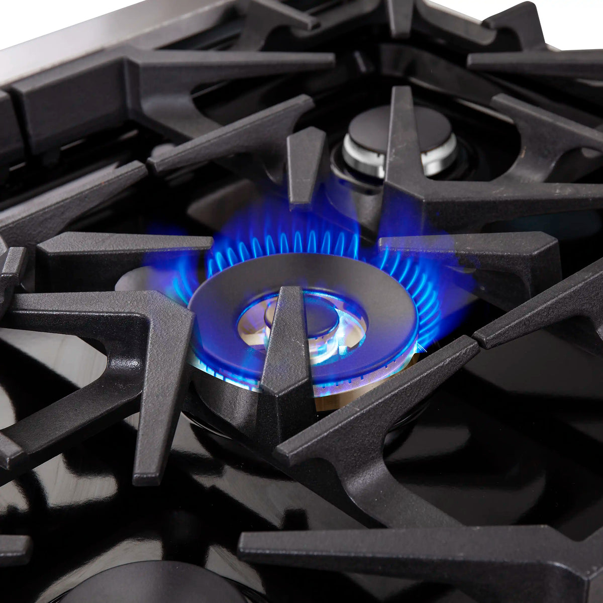 Gas burner flame on black cooktop with central burner cap
