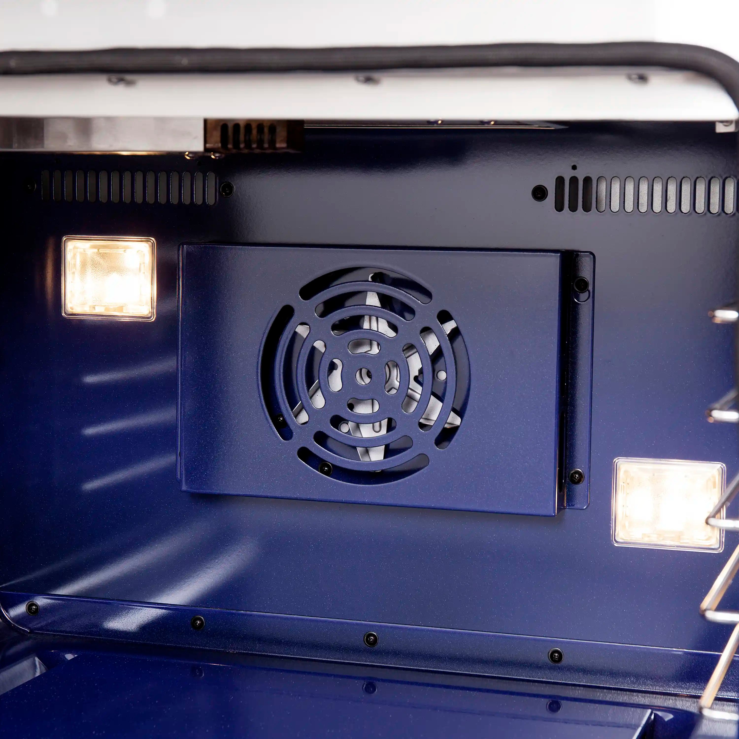 Gas oven door opened showing fan grille and two interior oven lights