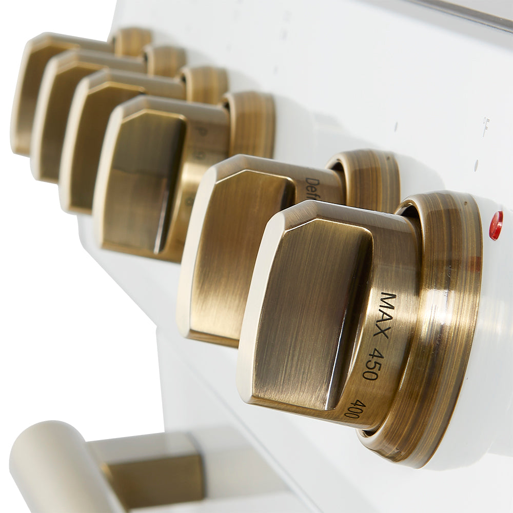 Close-up of antique brass control knobs on a white induction range
