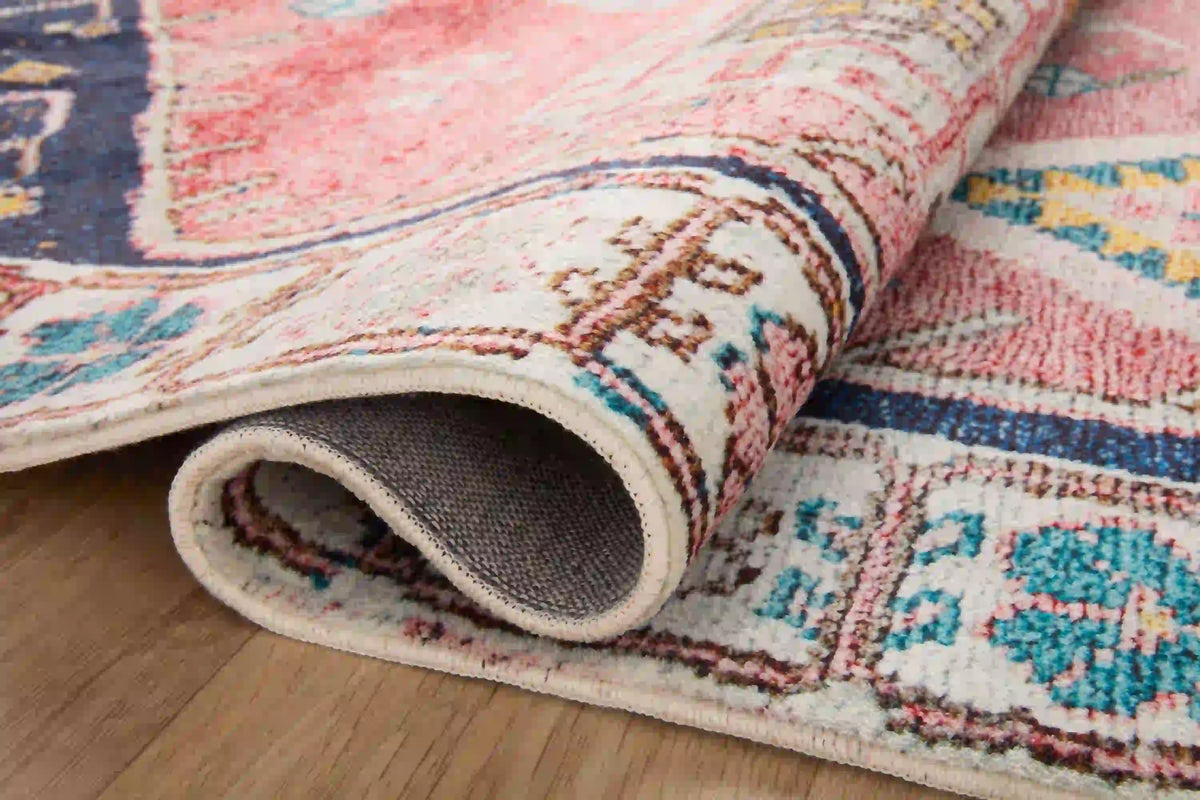 Rolled edge of multicolor patterned area rug with navy and rust tones