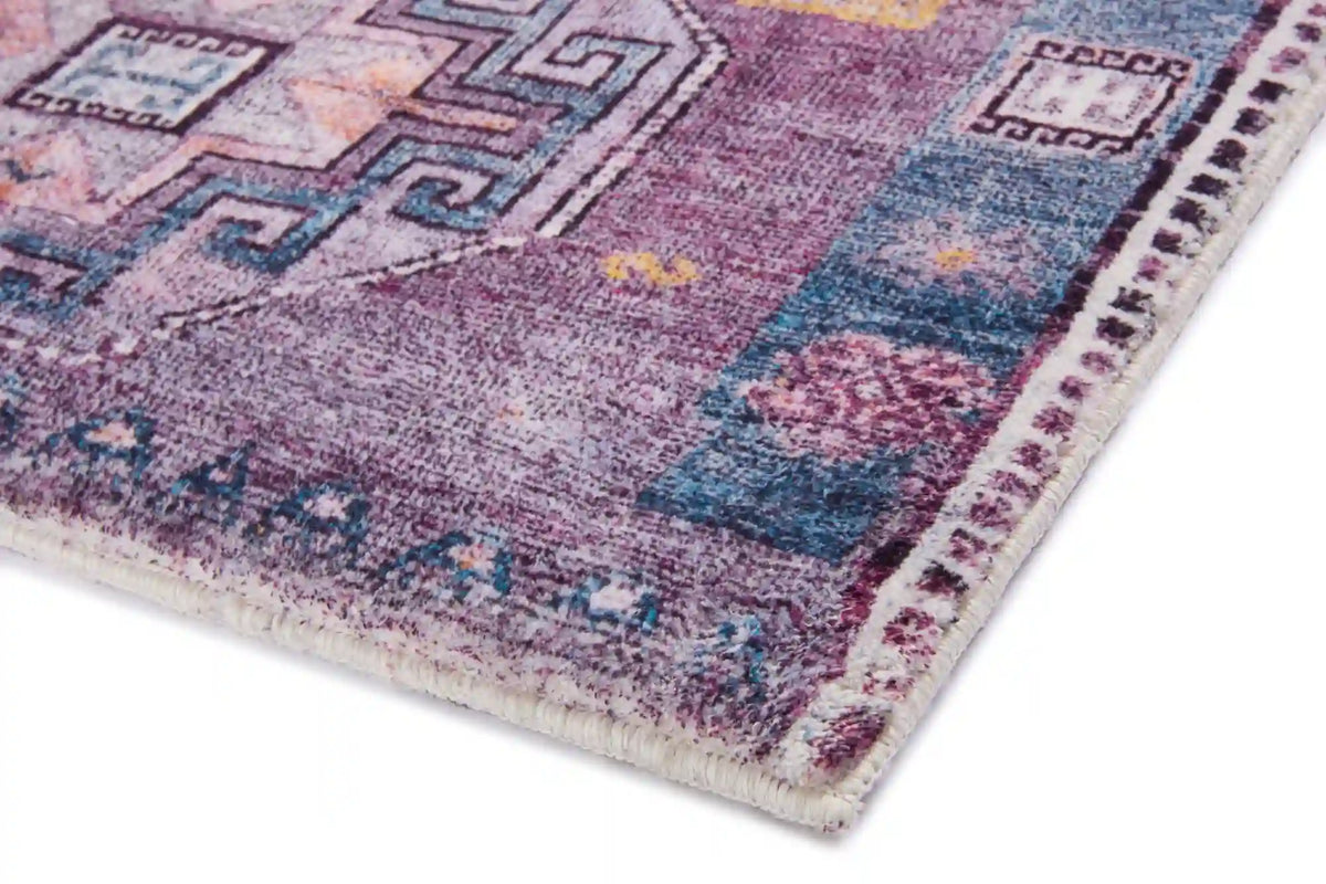 Close-up of purple-blue textured accent rug with multicolor geometric trim and worn look