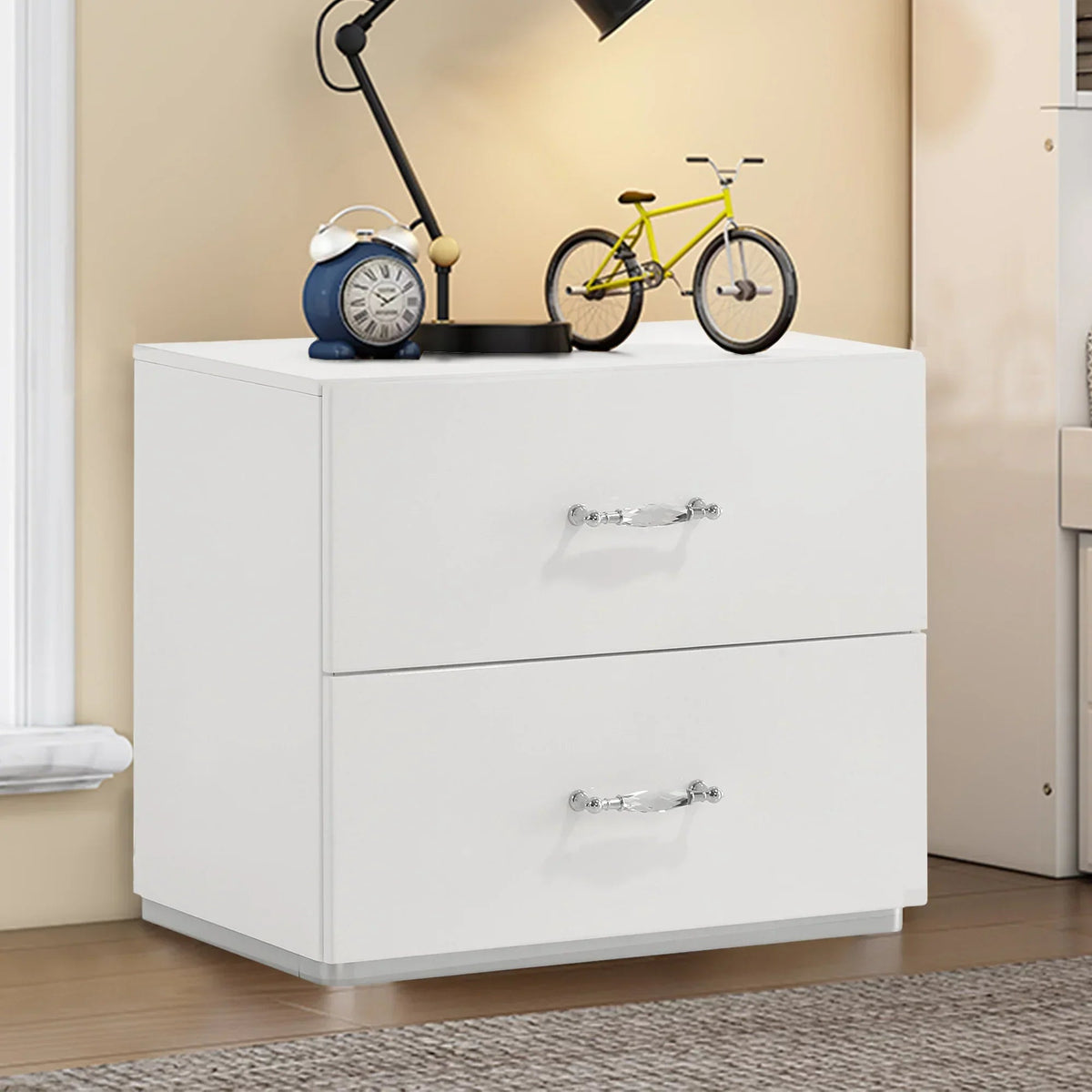 White 2-drawer nightstand with chrome pulls, styled with decor items on top.