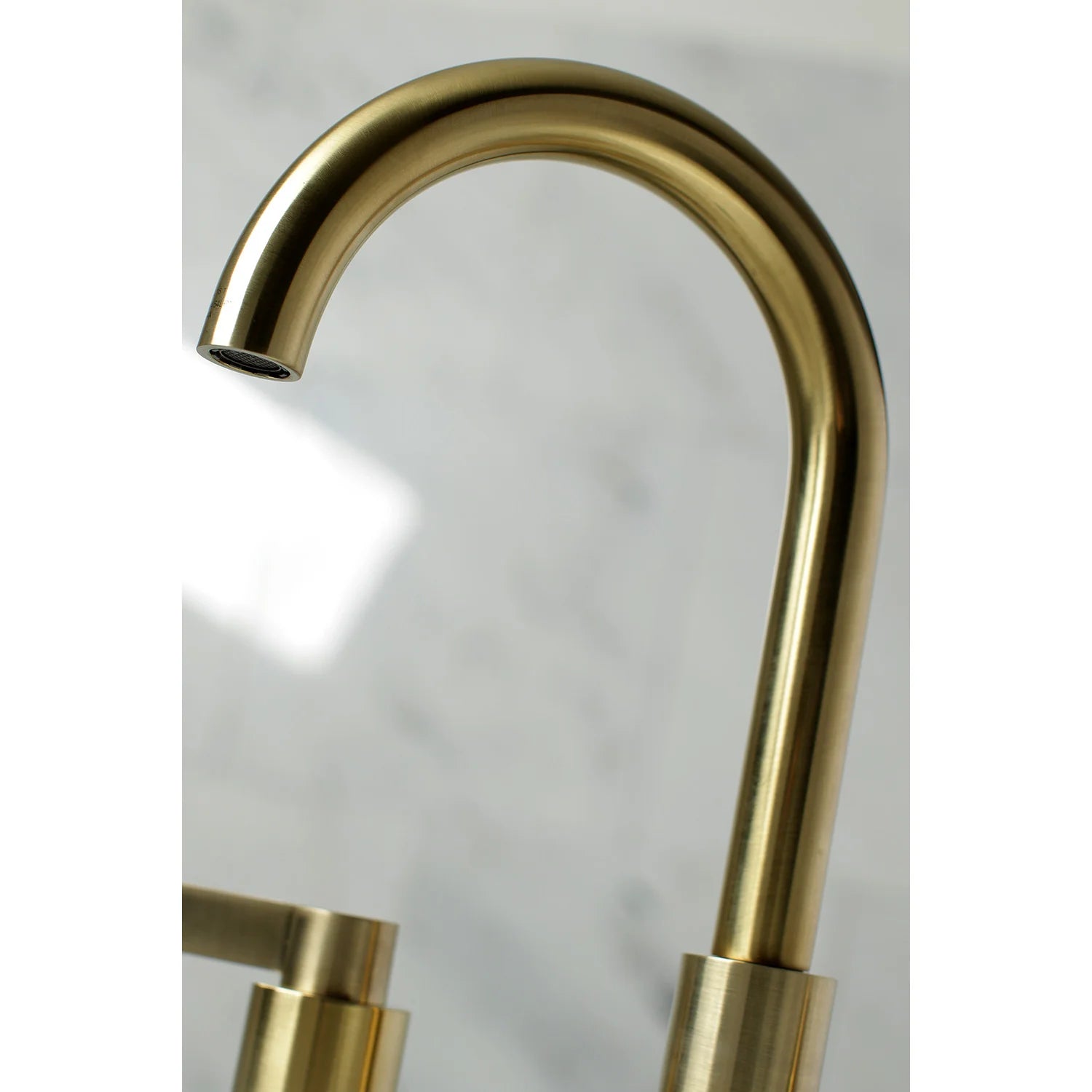 Brushed brass curved faucet spout with smooth cylindrical base