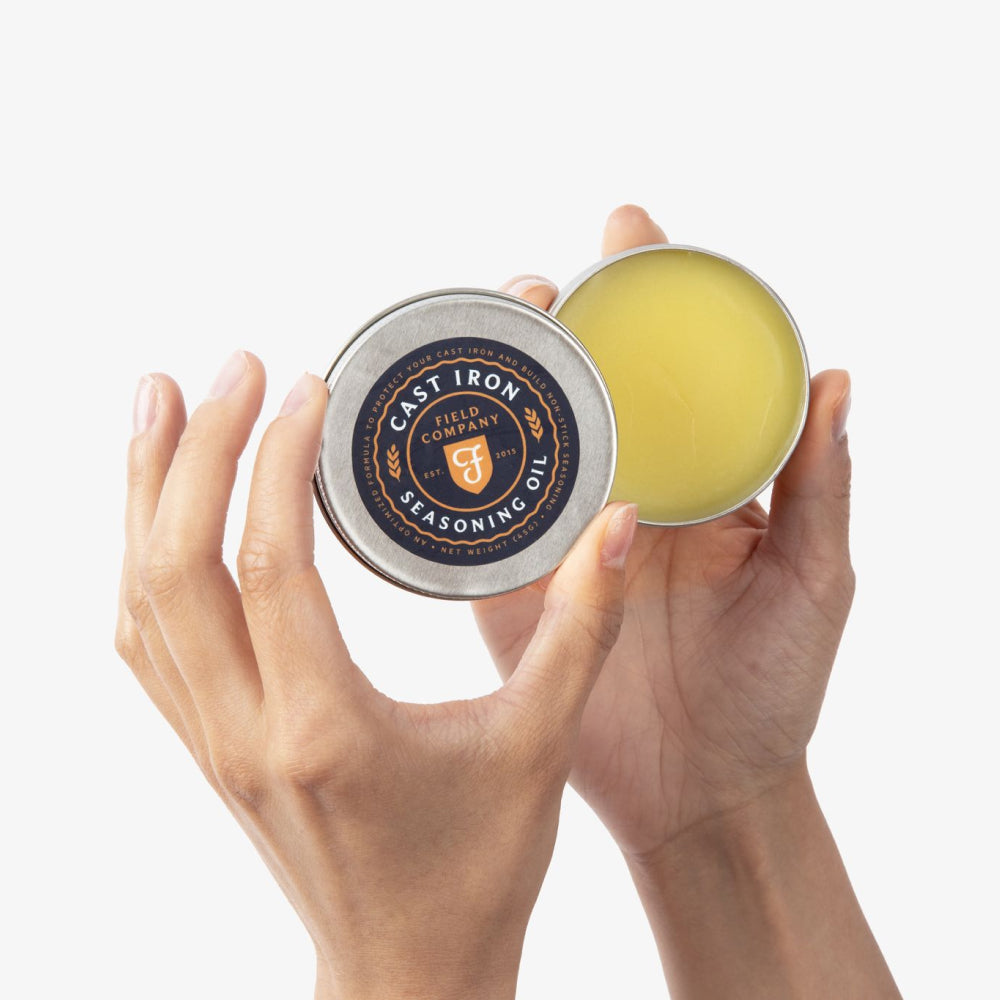 Cast-iron seasoning tin with yellow seasoning, held in hands