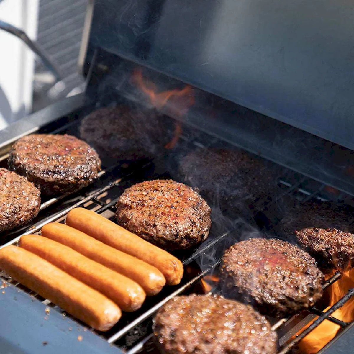 Open-top propane grill with sausages and burgers on grates