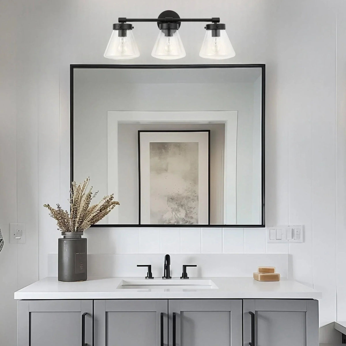 Black 3-light vanity light with clear glass shades mounted on a bar