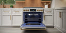 Stainless gas range with oven door open, bronze trim visible, burners above