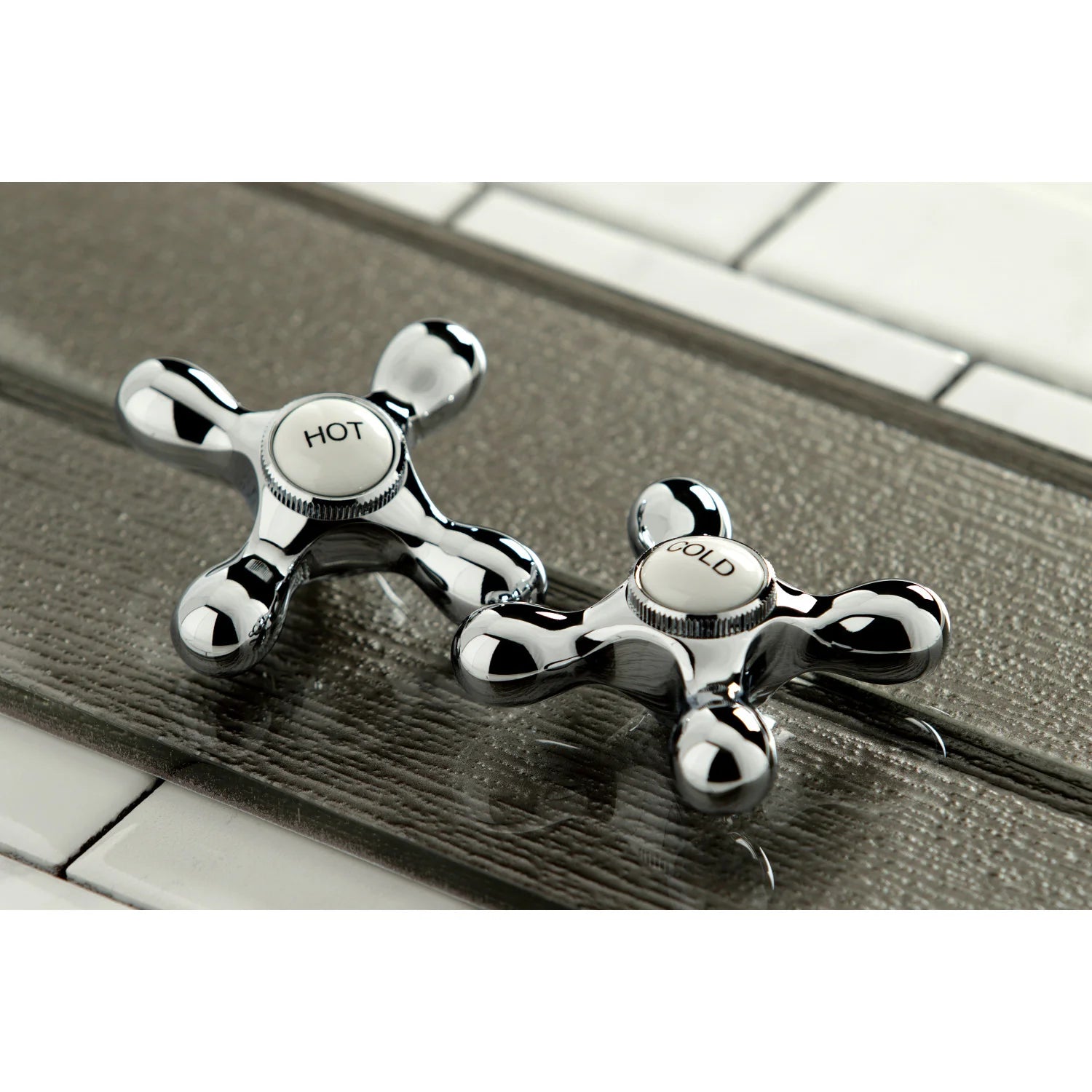 Polished chrome hot and cold lever handles on a wall-mounted kitchen faucet
