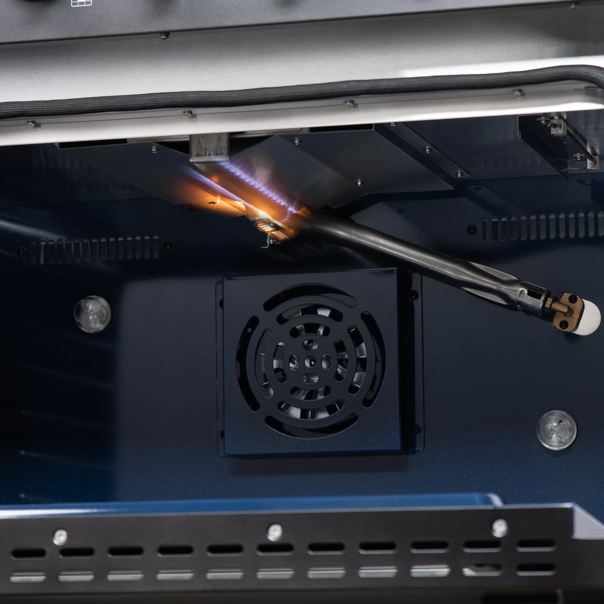 Open oven shows convection fan and gas burner flame tube above black range cavity