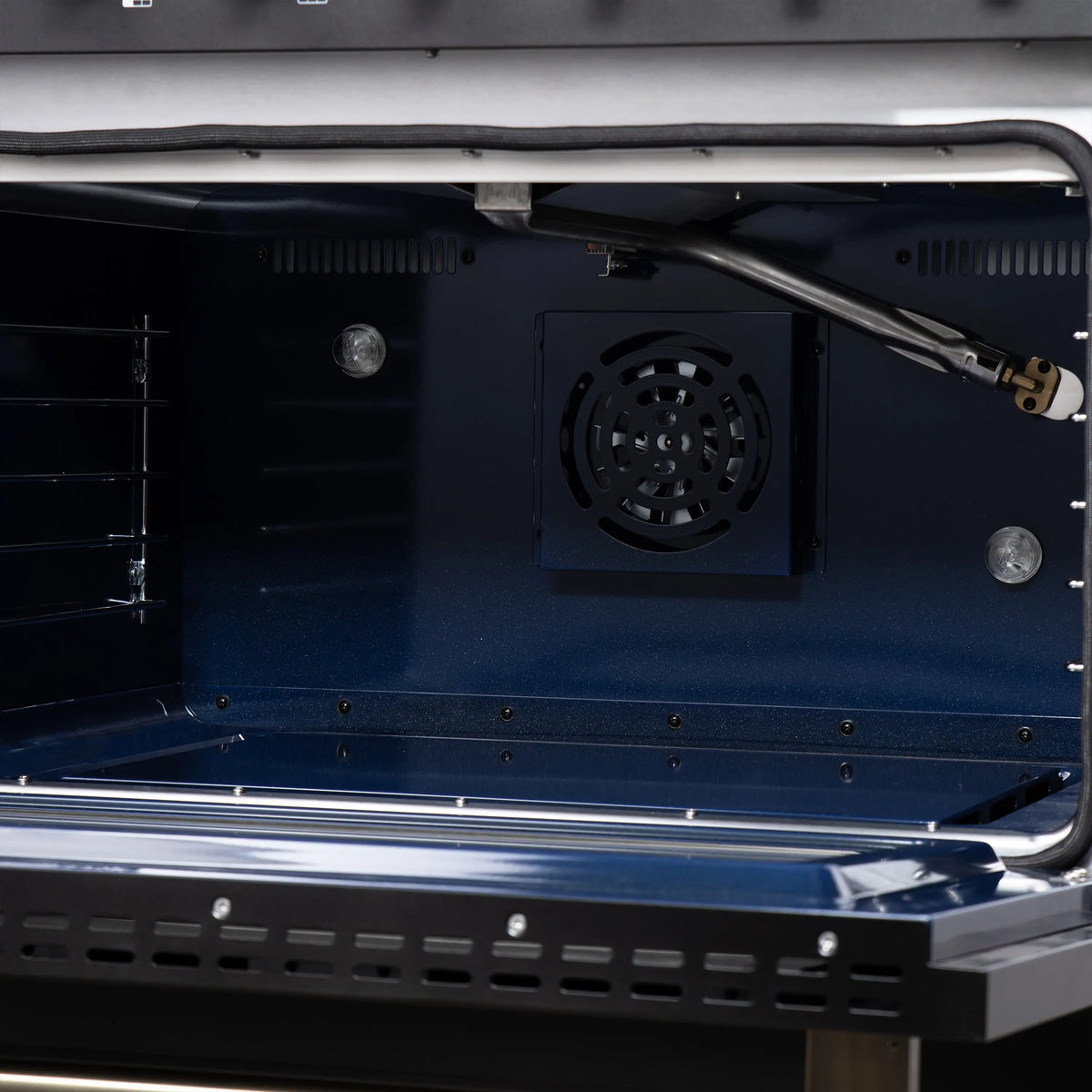 Open convection oven cavity with fan and burner igniter inside black freestanding gas range